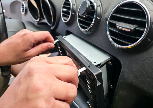 Man using removal keys to pull car stereo head unit out of dashboard for repair process