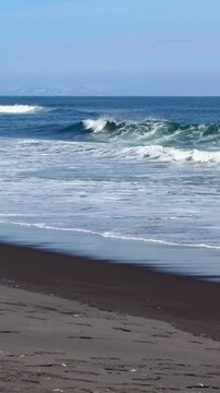 Pacific Ocean waves break onto black volcanic sand at Khalaktyrsky Beach in Kamchatka. Powerful surf, wild coastline and endless horizon convey natural energy, freedom, solitude and remote travel