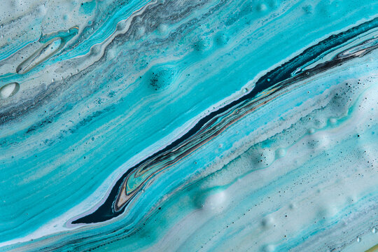 Smooth diagonal streams turquoise, white, and black paint creating marble liquid background.