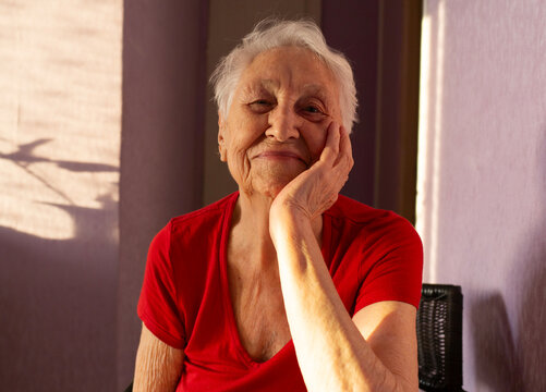 The portrait of a cheerful smiling senior woman over home background