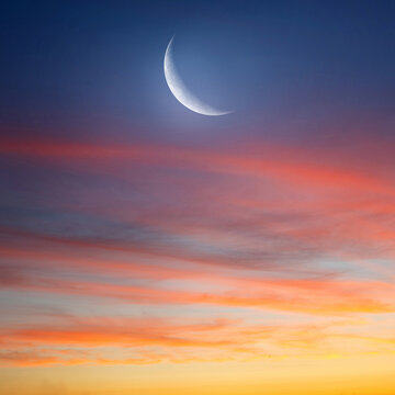 Peaceful sunset sky with soft clouds and a crescent moon. Symbolic night scene often associated with Islam, Muslim culture, religion, and spiritual meaning.