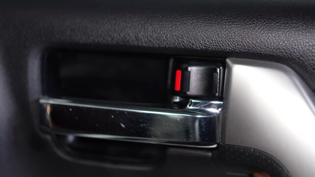 Car interior door handle chrome lever with red lock switch.
