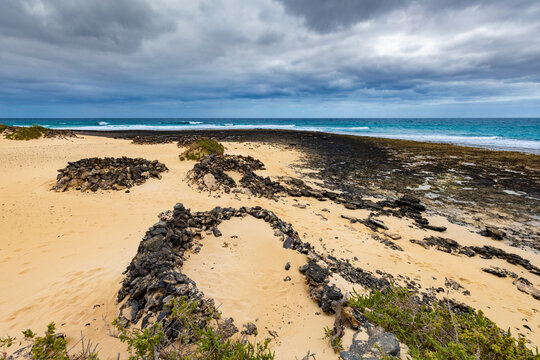 Panoramic view of a volcanic beach and the turquoise Atlantic Ocean under a blue sky on Fuerteventura (Canary Islands) &ndash; a background or wallpaper for your project