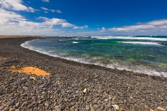 Panoramic view of a volcanic beach and the turquoise Atlantic Ocean under a blue sky on Fuerteventura (Canary Islands) &ndash; a background or wallpaper for your project