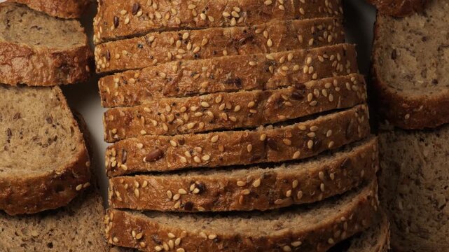 Sliced whole grain bread rotating on white background