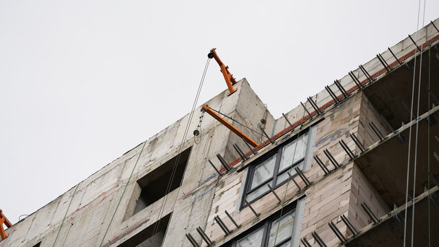 Unfinished multistory concrete building with open structural sections during active construction, showing high rise development and structural work at height