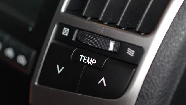 Car climate control panel buttons for temperature adjustment (TEMP) with up and down arrows, located right below an air vent adjustment thumbwheel.