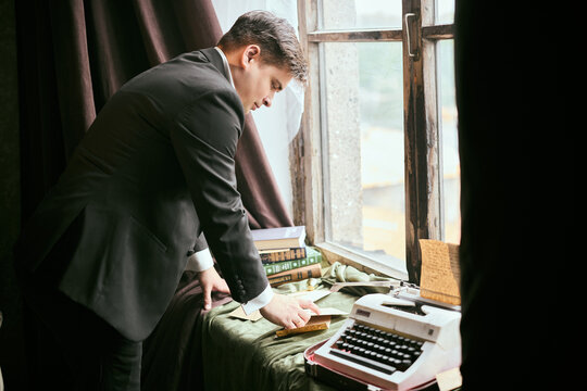 Cautious man scrutinizes documents in subdued lighting carefully