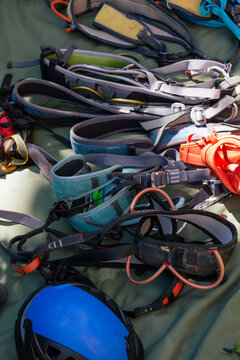 Climbing gear and harnesses lay on green tarp