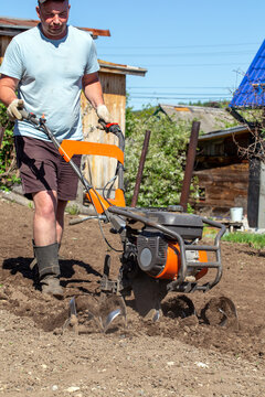 Male farmer plows the land with a cultivator. Agricultural machinery for tillage in the garden