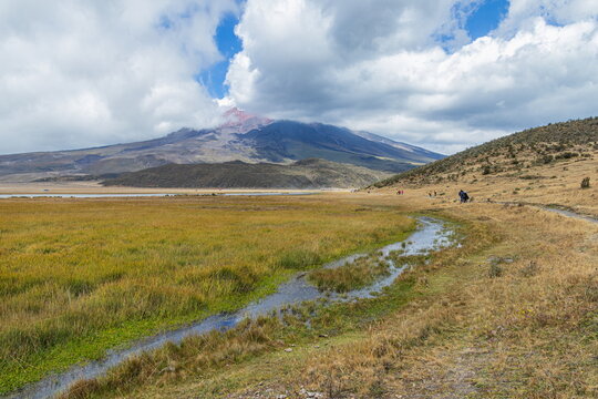 A beautiful panoramic view the majestic, snow-capped Cotopaxi active volcano partially covered by clouds and of the lake Limpiopungo in Cotopaxi National Park, Ecuador