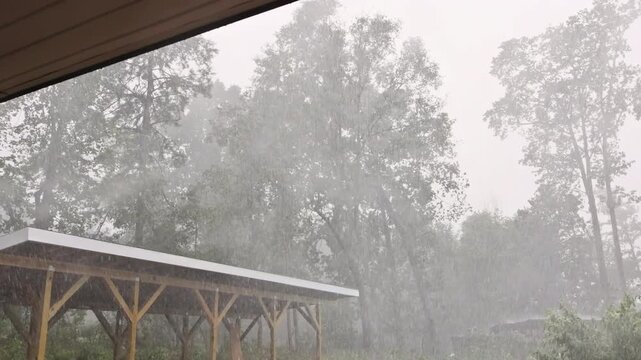 Heavy rain floods ground near shed as during thunder storm, in quiet countryside setting.