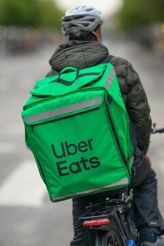 Gothenburg, Sweden - July 28 2026: Uber Eats bicycle courier carrying green delivery backpack.