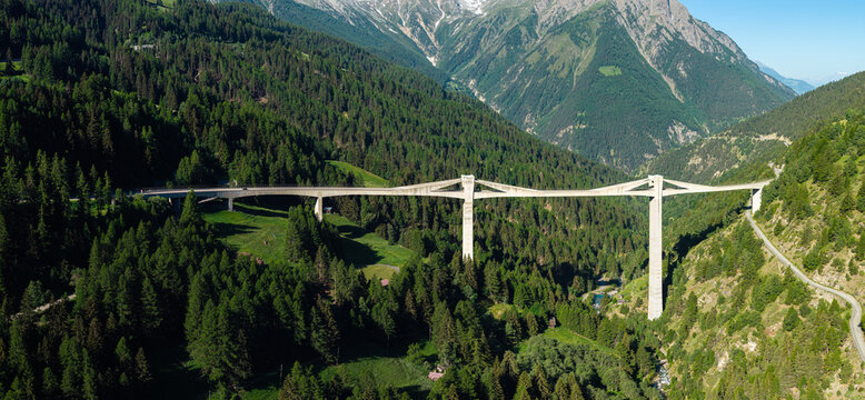 Aerial drone panoramic view of the spectacular concrete Ganter Bridge (Ganterbr&uuml;cke) spanning a dense green pine forest valley on the Simplon Pass road in Valais, Switzerland.
