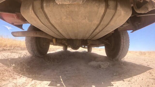 Undercarriage of rugged vehicle navigating sandy desert floor