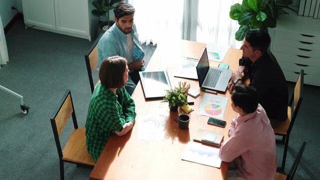Skilled project manager walking at table while colleague brainstorm idea. Business team working together to plan marketing strategy while looking at data analysis or financial statistic. Convocation.
