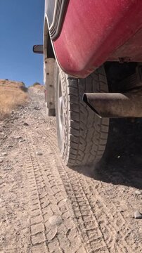 Off-road truck navigating rugged, rocky desert trail under bright sun