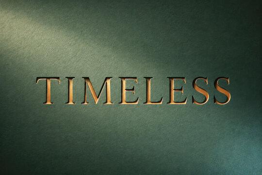 Timeless Word Carved in Copper on Green Cardboard with Dramatic Light