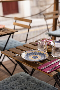 colorful place setting with burgundy napkin and patterned plate at outdoor restaurant on a small street