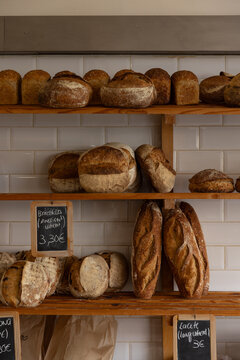 hip Portugese bakery selling fresh baked bread loaves, white tile, chalk signage, and minimal wooden shelves