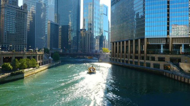 Scenic view of the Chicago River flowing through downtown, featuring iconic skyscrapers, historic bridges, and tour boats navigating the urban waterway on a sunny day.