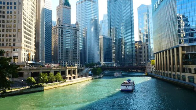 Scenic view of the Chicago River flowing through downtown, featuring iconic skyscrapers, historic bridges, and tour boats navigating the urban waterway on a sunny day.
