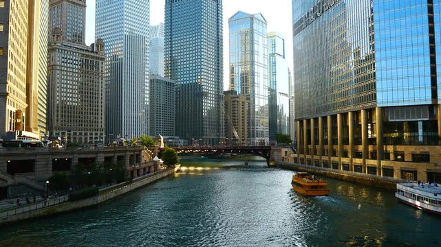 Scenic view of the Chicago River flowing through downtown, featuring iconic skyscrapers, historic bridges, and tour boats navigating the urban waterway on a sunny day.