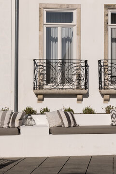vertical shot of built in outdoor seating with throw pillows at a traditional building with old balcony restored into an elegant boutique hotel