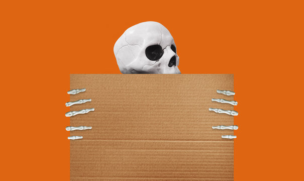 White skull and skeleton hands holding a blank cardboard sign against an orange background