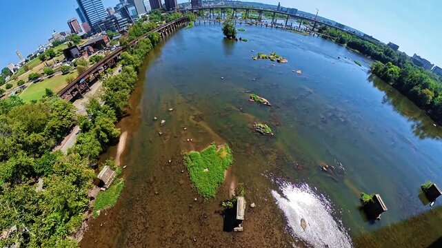 Banked aerial reveal explores james river and surrounding scenery in Richmond Virginia during daytime.
