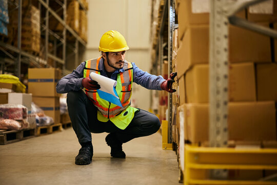 Young worker checking stock in warehouse storage room.