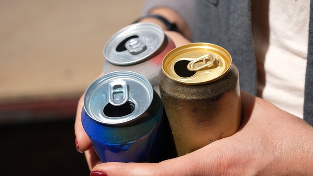 Woman holding empty soda and beer cans after party