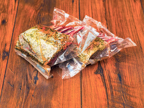 Two marinated rack of lamb in vacuum pack for extra freshness. Premium top quality lamb meat on wooden board. Butcher craft and skill. Technology to keep the product flavor and tasty