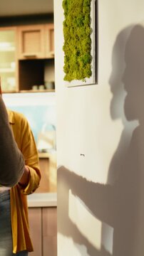 Vertical screen: Close up of a couple putting decorations on the wall in their new house, creating a personal cozy atmosphere in their first home while enjoying the satisfaction of redecorating.