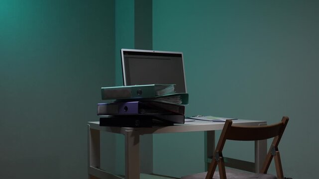 Business person in an office carrying a stack of binders and documents, working overtime on a computer, depicting a heavy workload and dedicated effort after hours