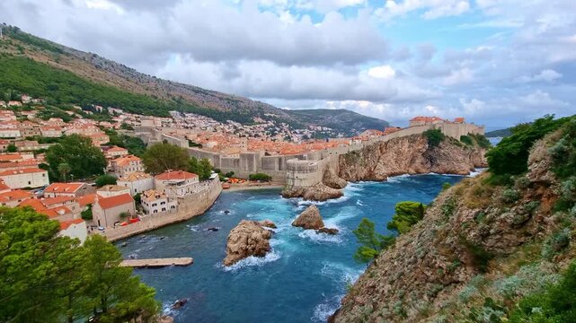 The historic city wall of the old town of Dubrovnik and the blue water of Adriatic Sea, in Croatia, in summer