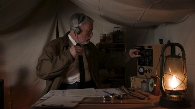 1930s man in a tent turning on and tuning a transmitter
