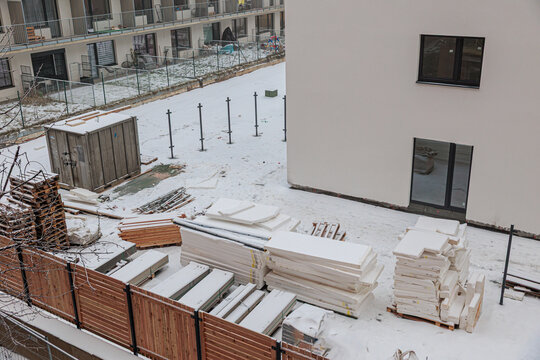 Residential Construction Site With Snow Covered Materials, Portable Toilets and Insulation Stacks