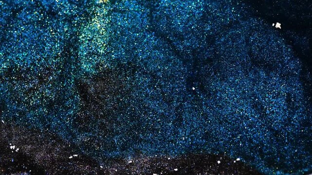Mixing alcohol ink in macro shot revealing vibrant blue patterns