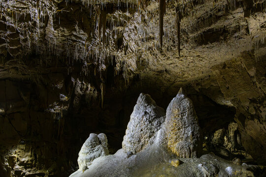 Illuminated "Drei Zinnen" (Three Peaks) stalagmite formation and hanging ceiling stalactites inside the Lurgrotte cave in Peggau, Styria, Austria