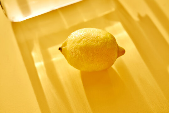 Lemon with glass shadows on yellow background