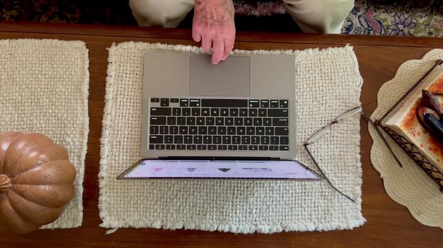 Overhead view of senior person using trackpad on laptop computer