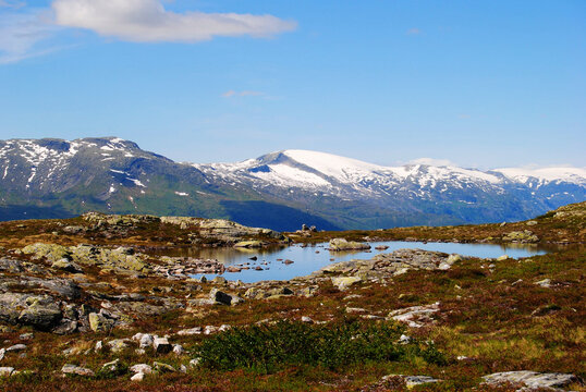 Alpine pond and snowcapped mountains near Molden summit in Norway