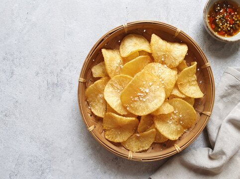 Traditional crunchy cassava chips or keripik singkong snack in a wooden bowl.