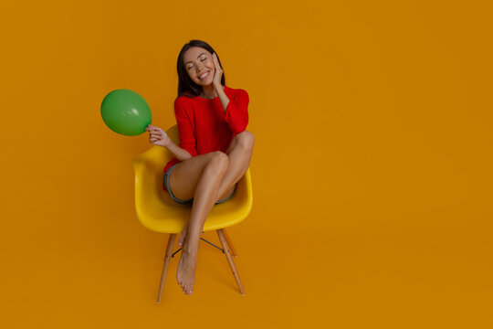 Delighted woman with green balloon enjoying festive celebration