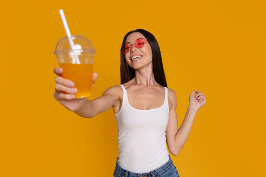 Happy woman offering refreshing cold drink to camera