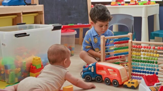 Two brothers playing with an abacus while a baby reaches and a toy truck sits on the floor in a playroom building; playful sibling bonding.