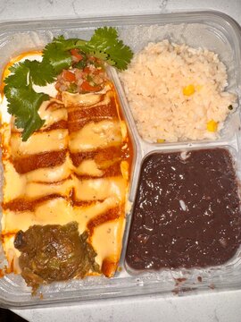 Mexican Enchiladas with Creamy Sauce Rice and Refried Beans Takeout Meal
