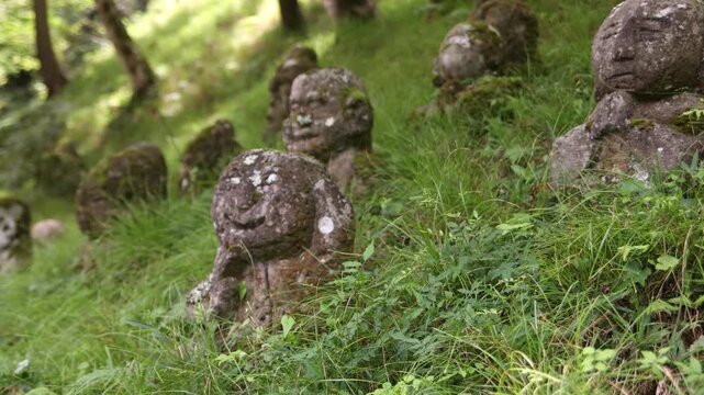 Weathered stone Buddhist figures among moss and greenery in Kyoto, creating an intimate spiritual detail of traditional Japanese temple culture and quiet contemplation