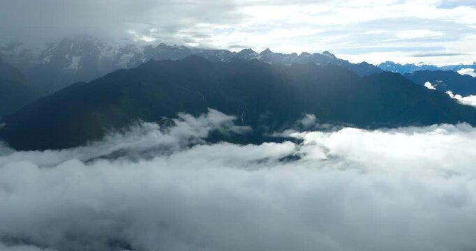Sindhupalchowk Nepal, Drone cruising over a dense cloud inversion above mountain valleys, revealing dark green Himalayan ridges and snow-dusted peaks stretching to the horizon near Panchpokhari trail.